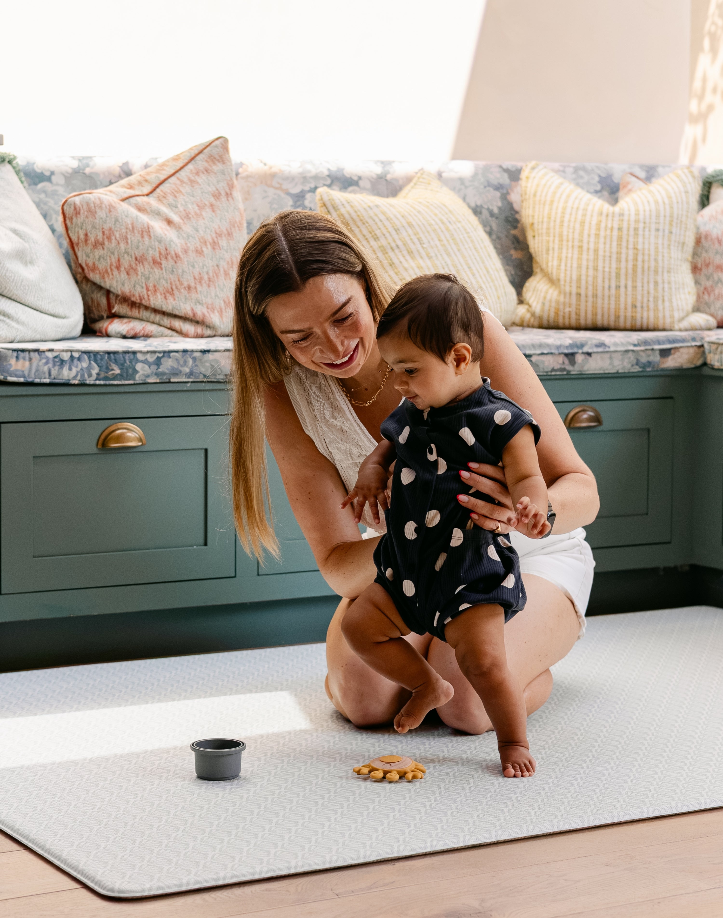 A woman helping her baby take some steps safely and comfortably on the totter and tumble playmat