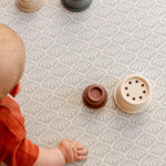 A close up of a baby's hands on the rug like safe non toxic The Beachcomber playmat from totter and tumble