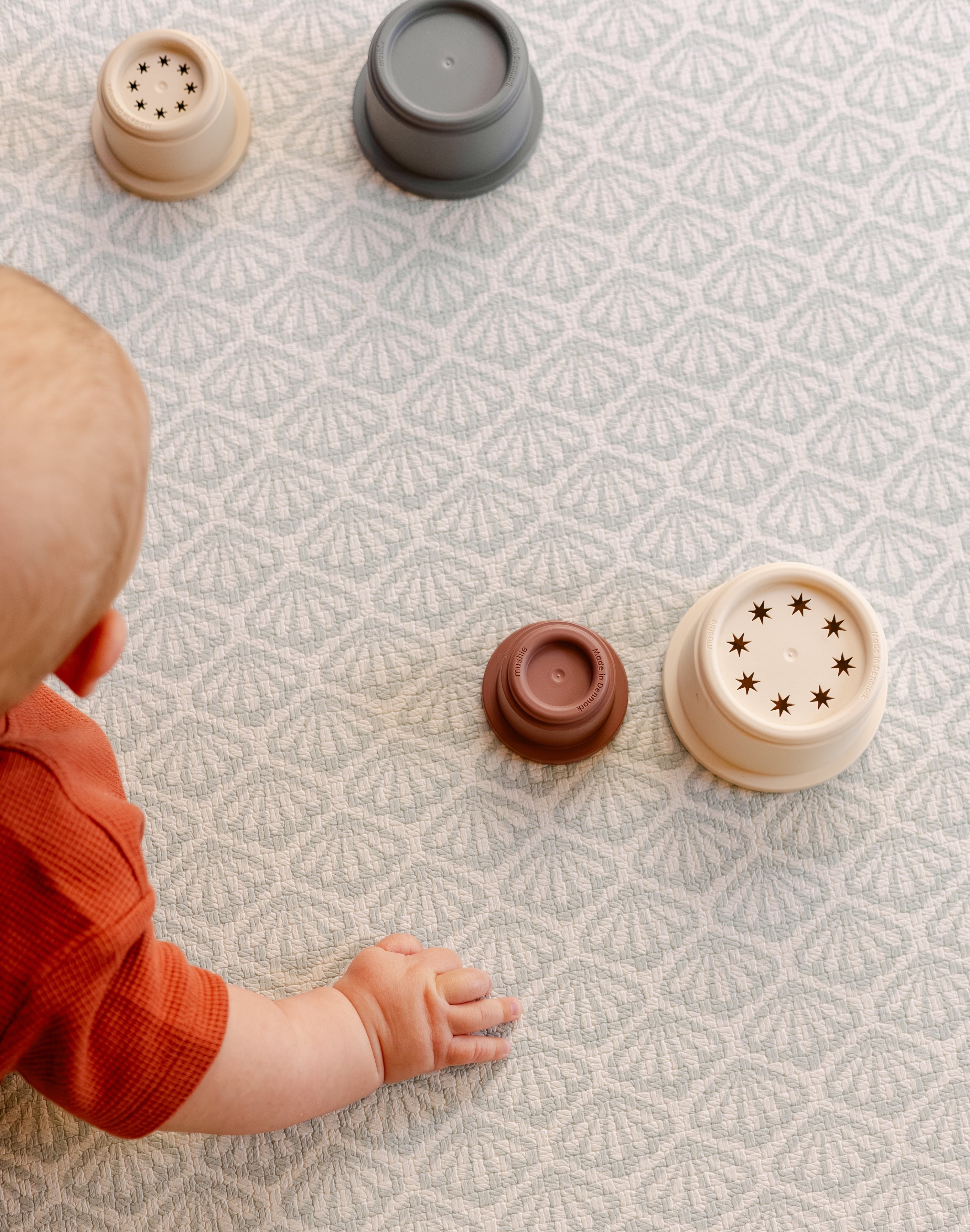 A close up of a baby's hands on the rug like safe non toxic The Beachcomber playmat from totter and tumble