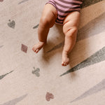Baby legs on The Counter, Totter + Tumble wipeable and reversible memory foam playmat