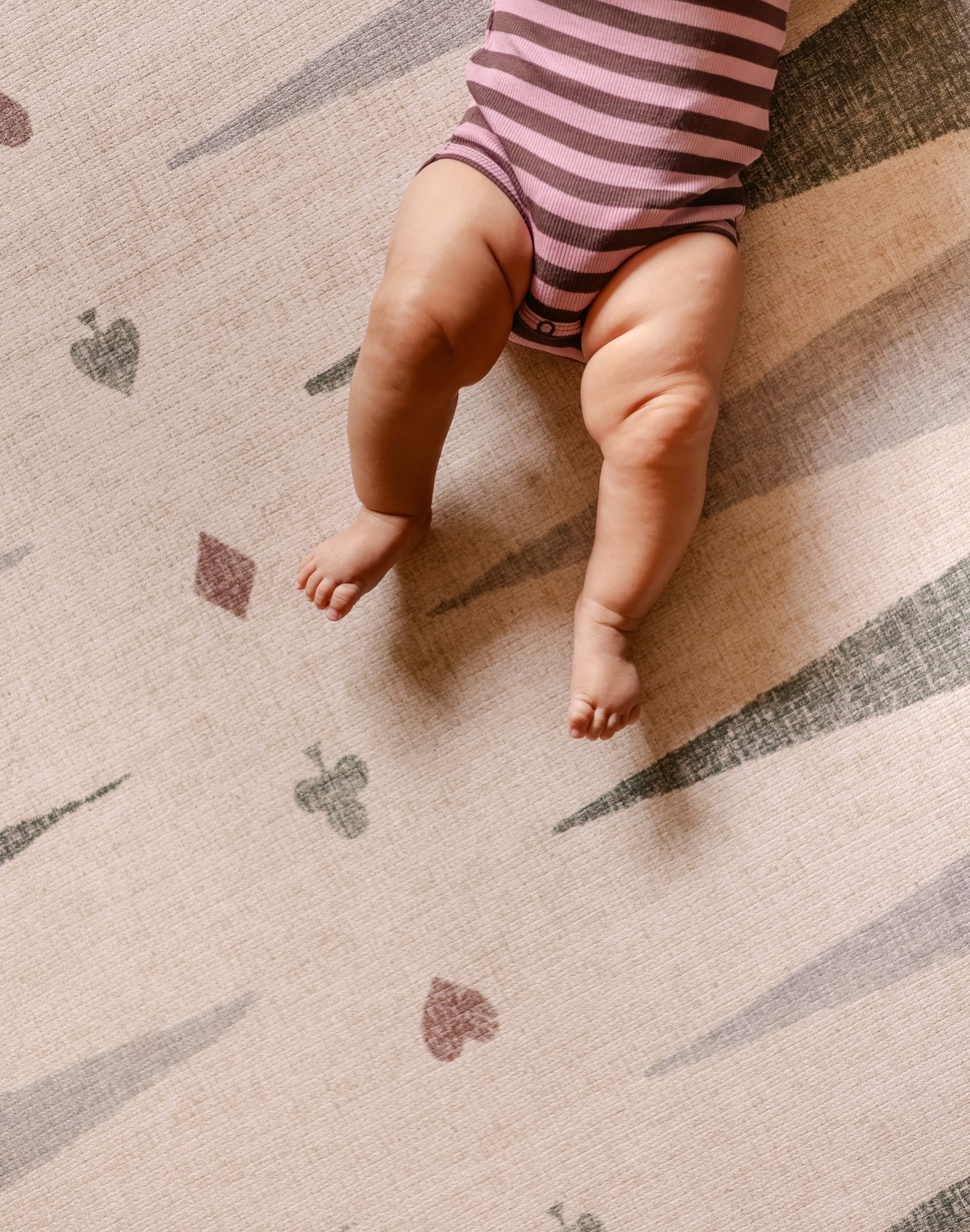 Baby legs on The Counter, Totter + Tumble wipeable and reversible memory foam playmat