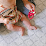 A baby sitting on a safe, comfortable memory foam geometric pattern playmat from totter and tumble 