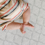Close up shot of a baby legs laid on a safe, non toxic, The Gatherer playmat from totter and tumble