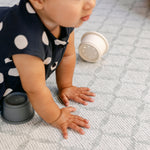 A baby pressing down on a thick memory foam playmat from totter and tumble