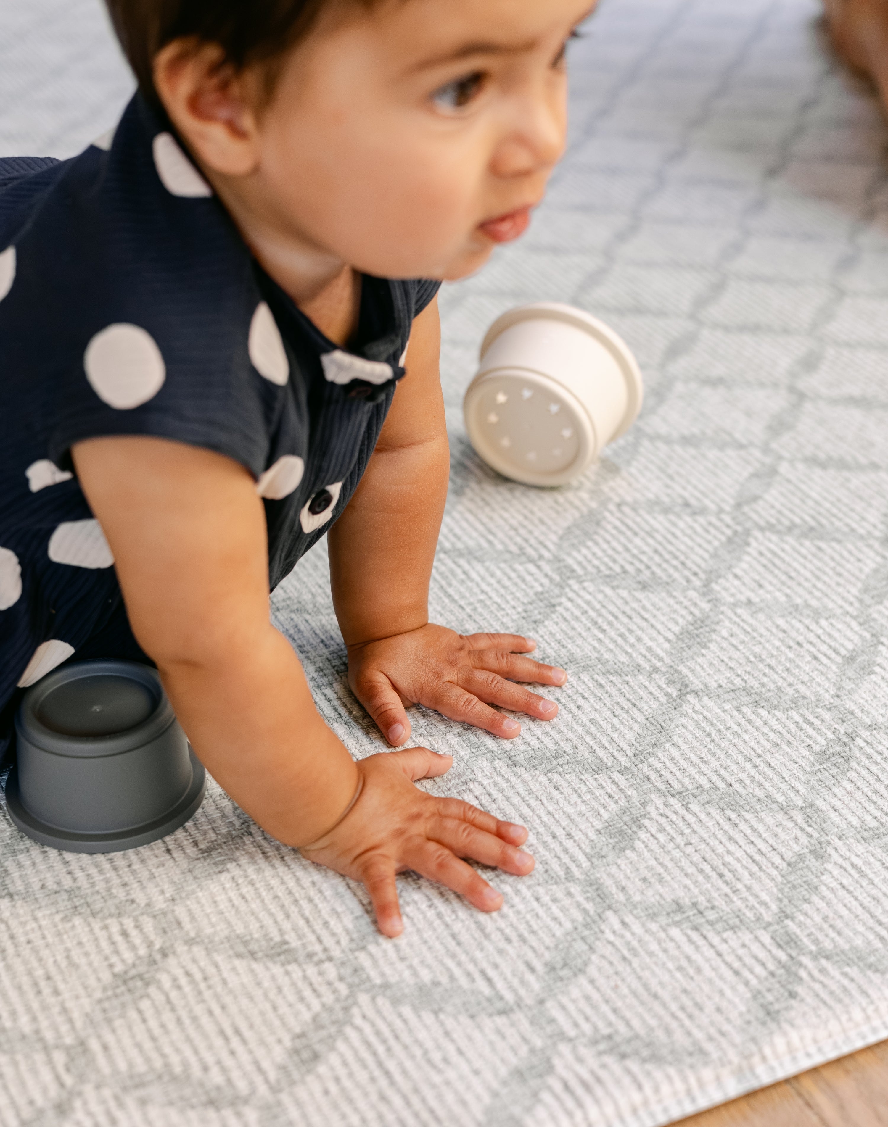 A baby pressing down on a thick memory foam playmat from totter and tumble