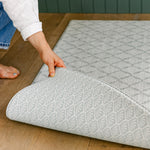 A person showcasing the reversible The Gatherer and The Beachcomber playmat, made from thick memory foam 