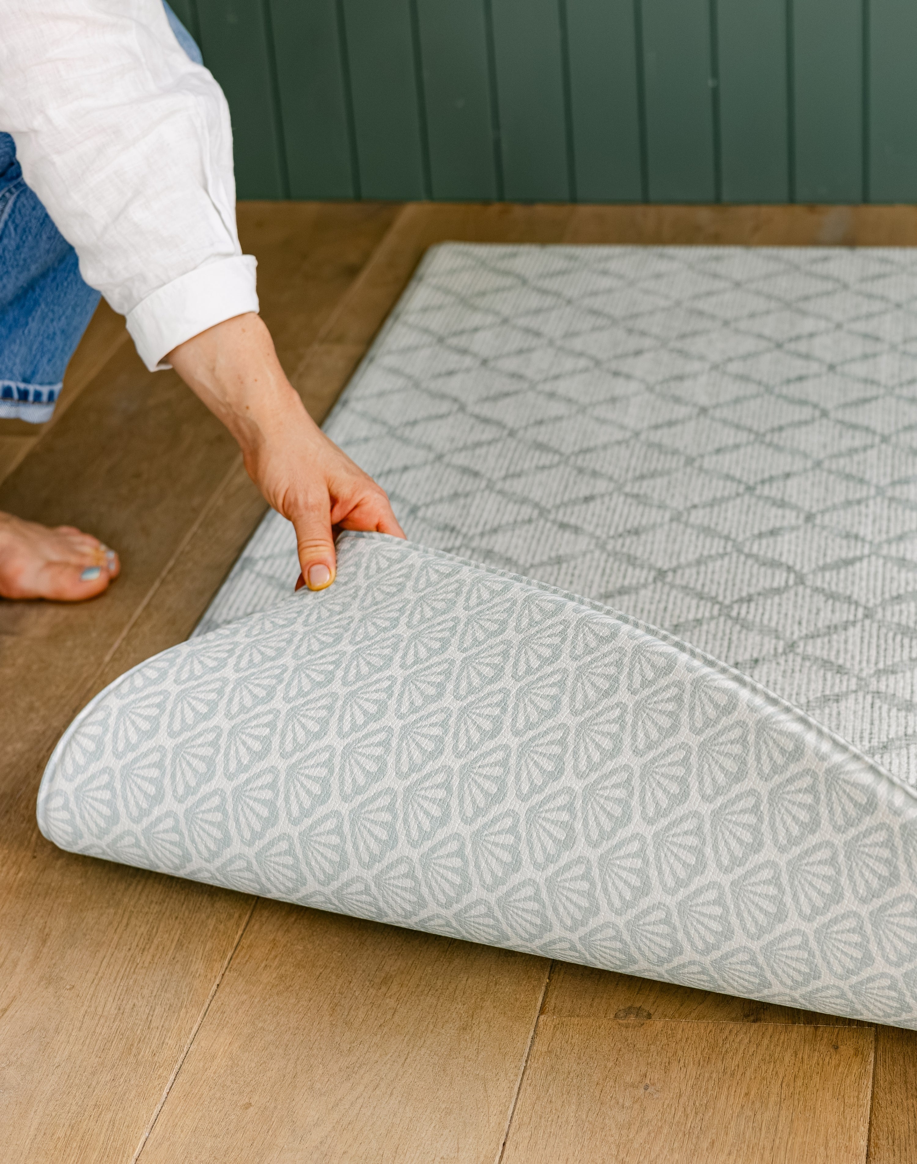 A person showcasing the reversible The Gatherer and The Beachcomber playmat, made from thick memory foam 