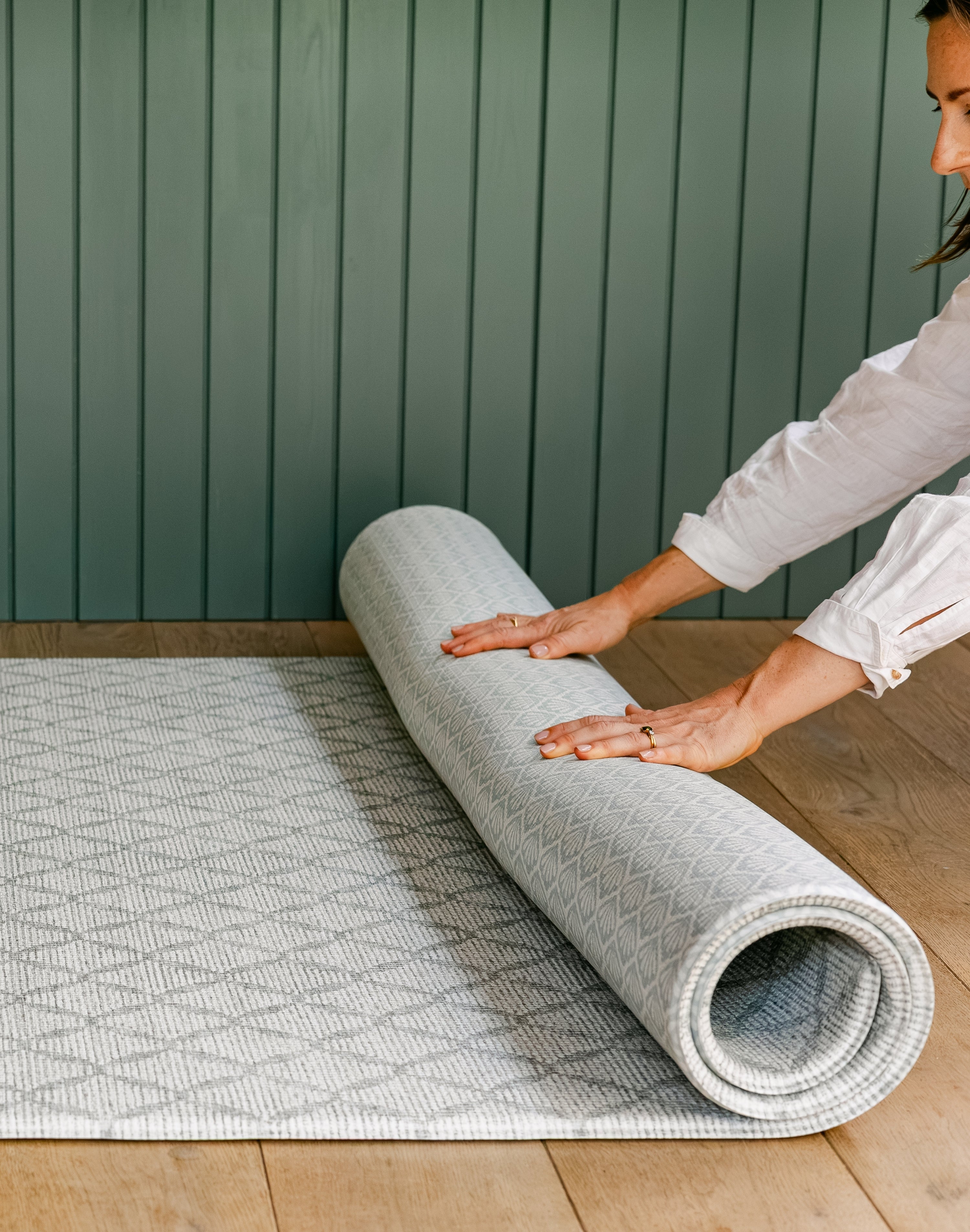 A woman unrolling the gatherer reversible playmat from totter and tumble with geometric pattern