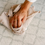 A close-up of a person's hand easily cleaning up a spill on the gatherer playmat from totter and tumble