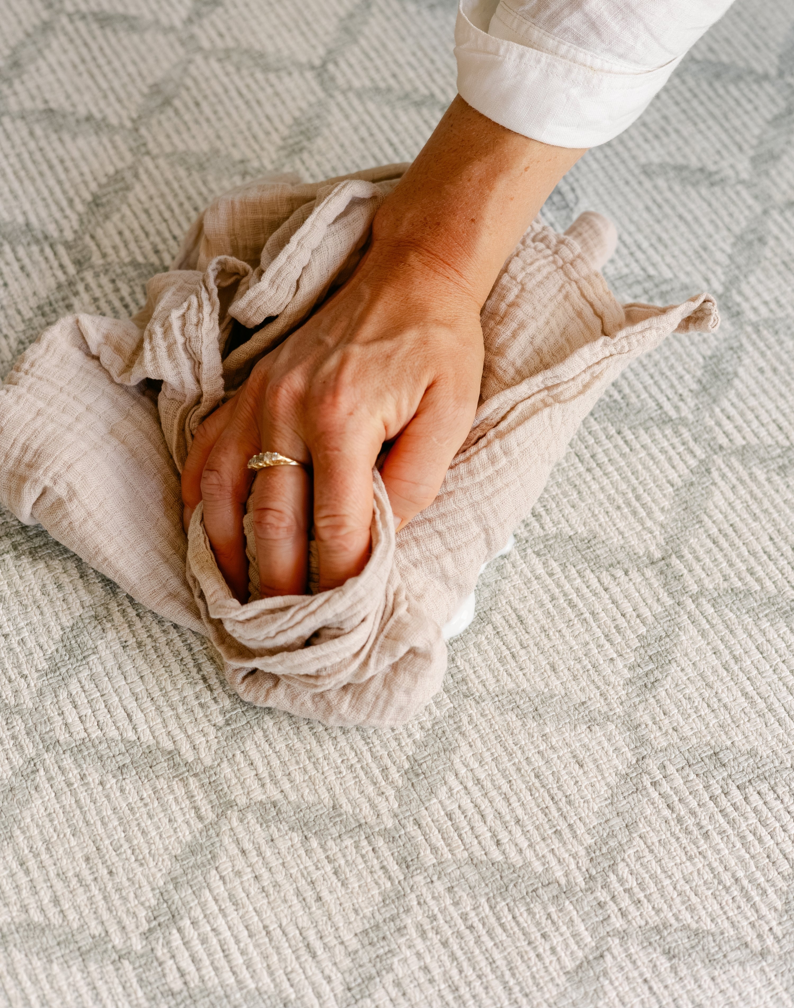 A close-up of a person's hand easily cleaning up a spill on the gatherer playmat from totter and tumble