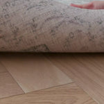 hand peels back a large padded playmat for hard floors to show it has a reversible design