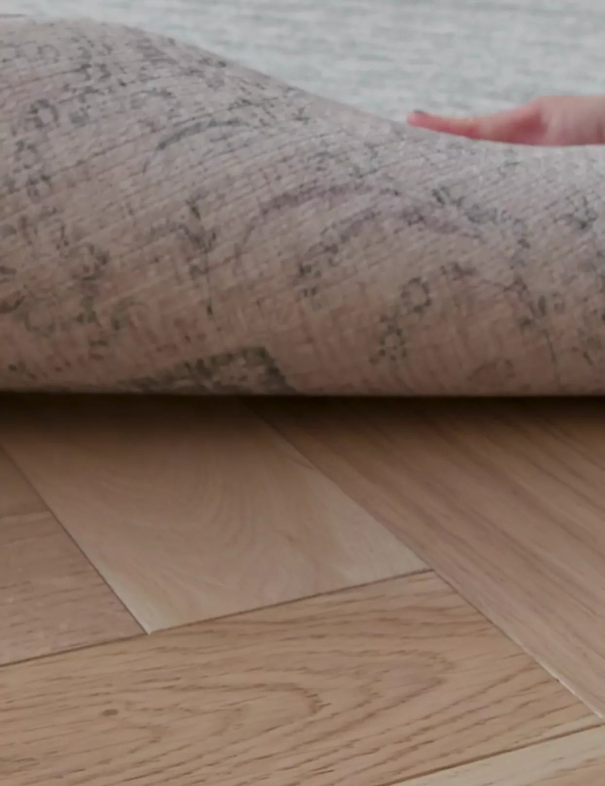 hand peels back a large padded playmat for hard floors to show it has a reversible design