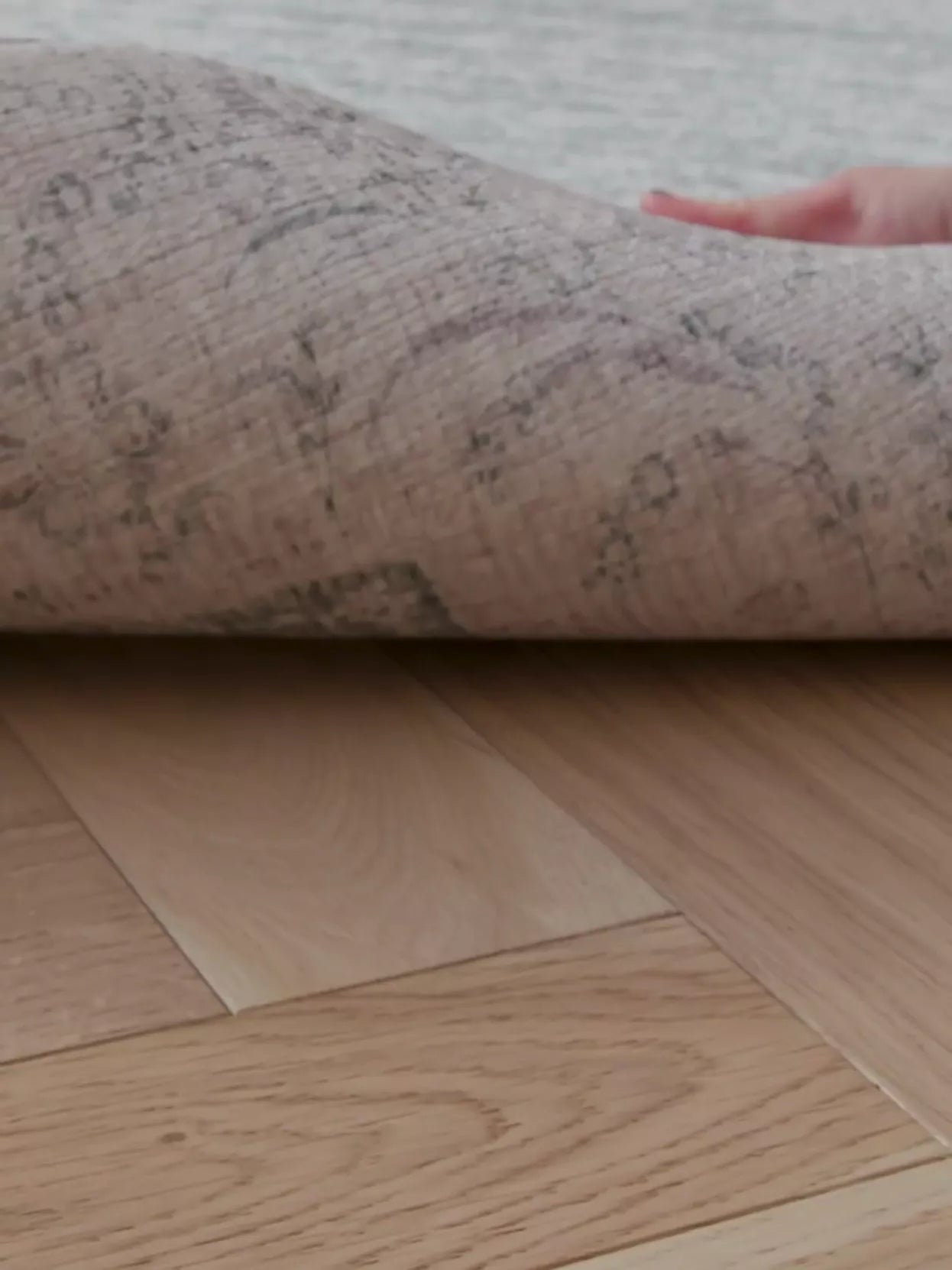 hand peels back a large padded playmat for hard floors to show it has a reversible design