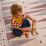 Child stacking blocks on The Roller Playmat by Totter + Tumble, the biggest one piece playmat on the market