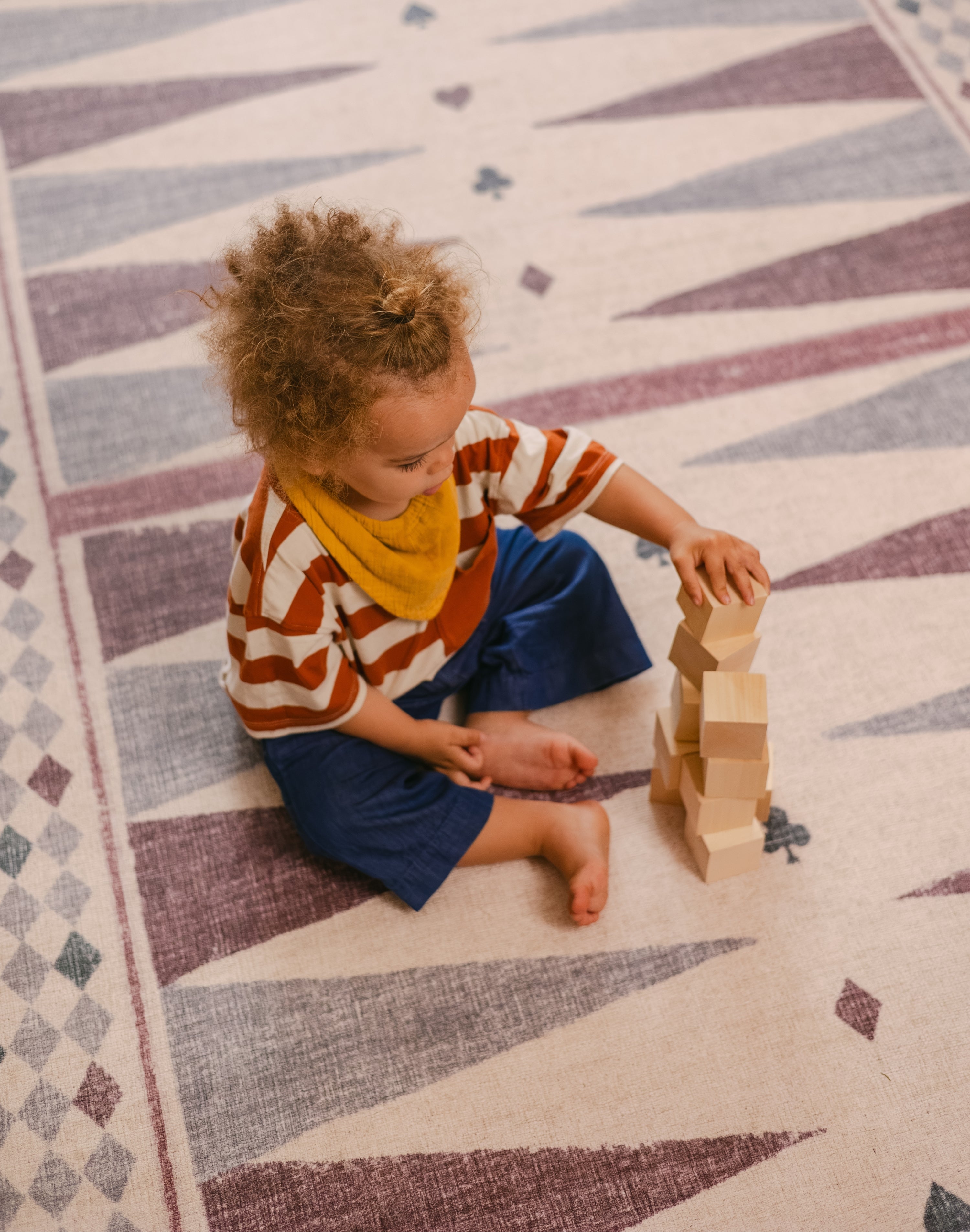 Child stacking blocks on The Roller Playmat by Totter + Tumble, the biggest one piece playmat on the market