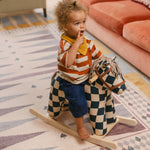 Child on rocking horse on The Roller Playmat by Totter + Tumble, the biggest one piece playmat on the market