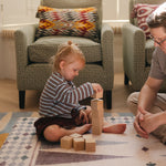 Child stacking blocks on The Roller Playmat by Totter + Tumble, the biggest one piece playmat on the market, watched by a man