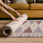 Hands rolling The Roller Playmat by Totter + Tumble, the biggest one piece playmat on the market, next to a bright yellow sofa