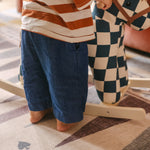 Toddler toes on The Roller Playmat by Totter + Tumble, the biggest one piece playmat on the market, next to a colourful rocking horse