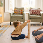 Child stacking wooden blocks on The Wildcard Totter + Tumble reversible wipeable memory foam playmat