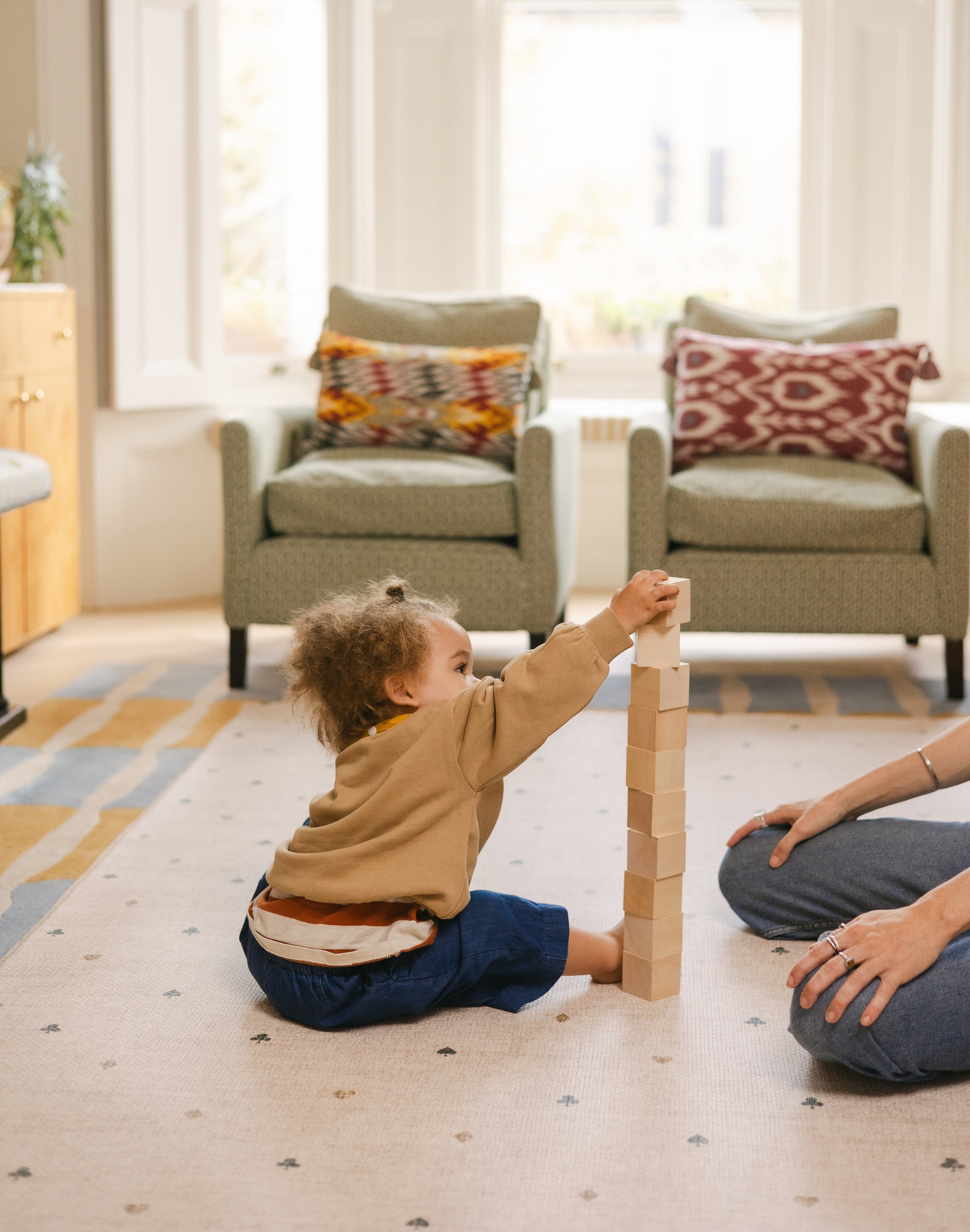 Child stacking wooden blocks on The Wildcard Totter + Tumble reversible wipeable memory foam playmat