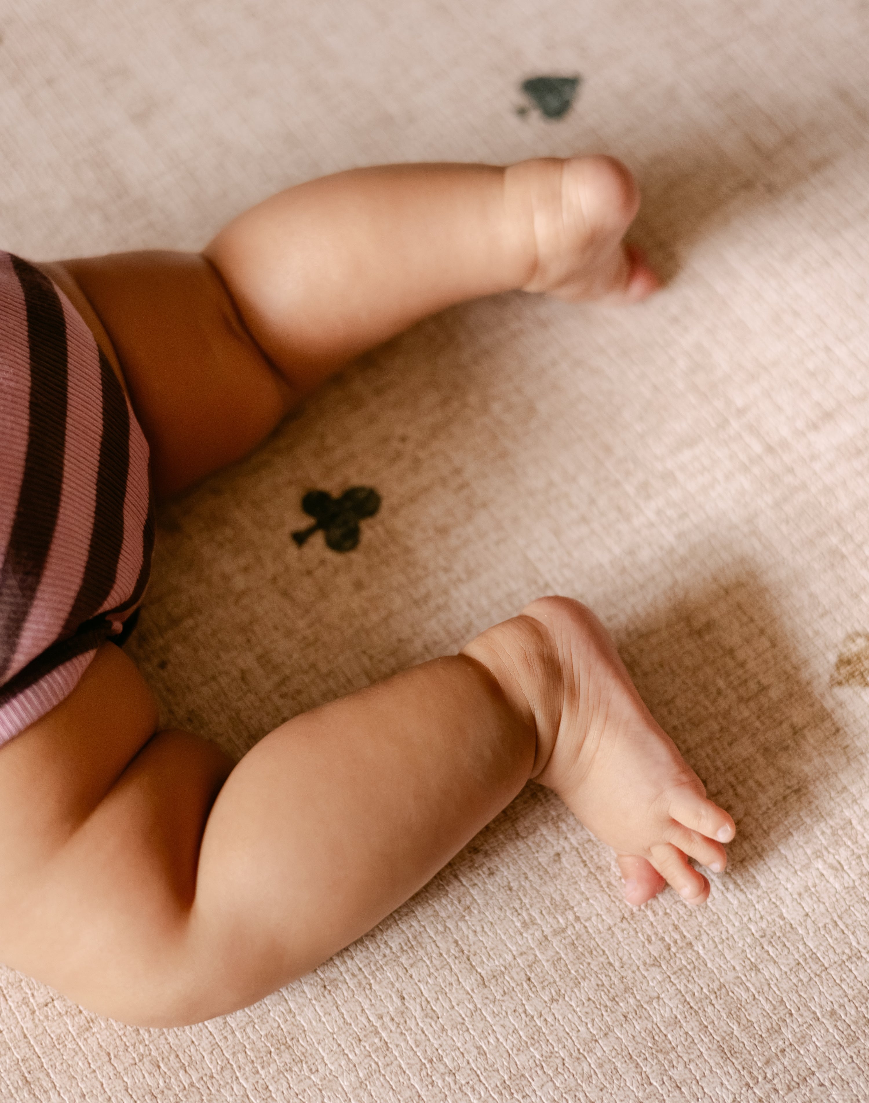 Baby's legs and toes lying on The Wildcard Totter + Tumble reversible wipeable memory foam playmat