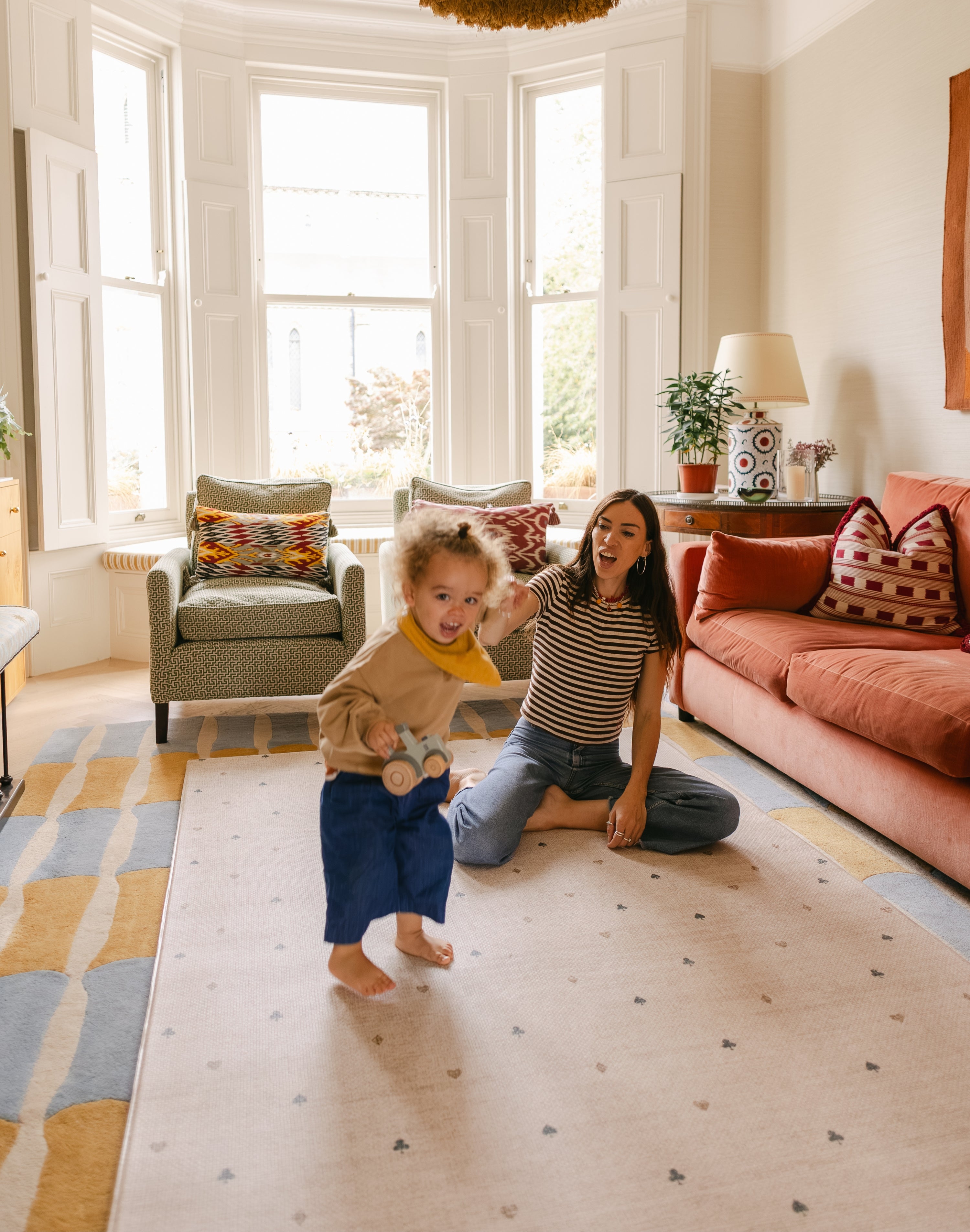 Mum and toddler playing on The Wildcard Totter + Tumble reversible wipeable memory foam playmat in a colourful living space