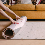 Rolling up The Wildcard Totter + Tumble reversible wipeable memory foam playmat against colourful sofa