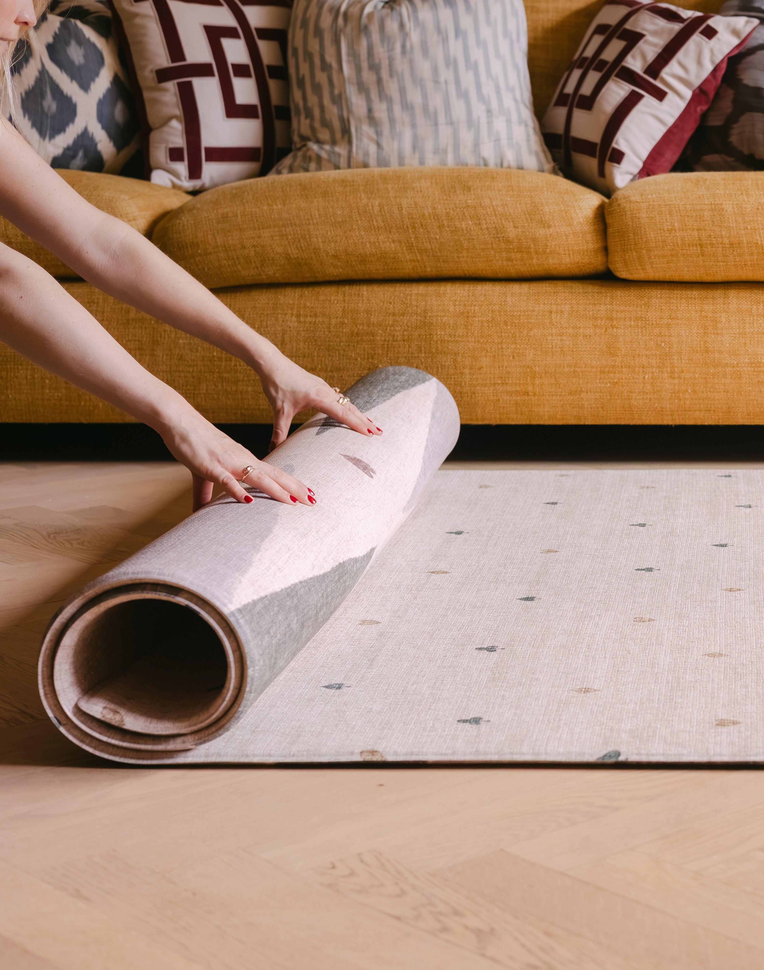 Rolling up The Wildcard Totter + Tumble reversible wipeable memory foam playmat against colourful sofa
